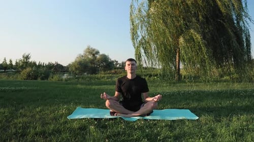 Man Meditating on Yoga Mat in Green Park