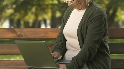Senior Woman Uses Laptop in Park