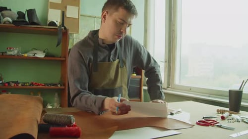 Focused Craftsman Tracing Shoe Pattern on Leather