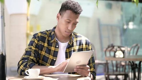 Young African Man Using Tablet Outdoor Cafe