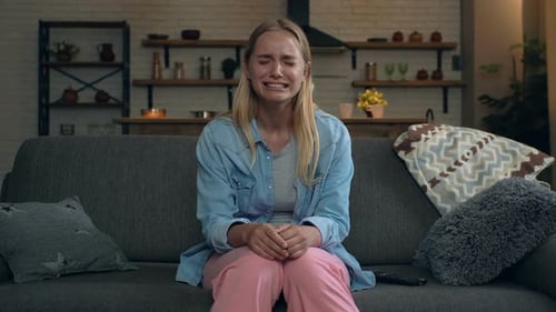 Young Woman Sitting On Couch Crying