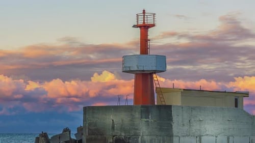 Ein wunderschöner Leuchtturm in einer Meereslandschaft, in der die Sonnenuntergangswolken wie ein Zeitraffer belebt sind, aber der