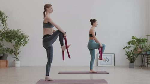 Women Stretching Leg with Yoga Straps in Studio