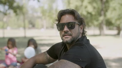 Front View of Smiling Man Fixing Glasses and Looking at Camera