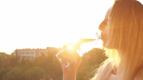 Woman Drinks Water During Golden Hour Outdoors