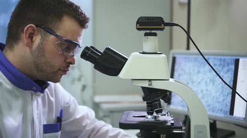 Scientist Analyzing Sample Using Microscope in Lab