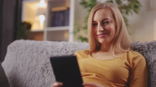 Woman Smiling and Using Tablet at Home