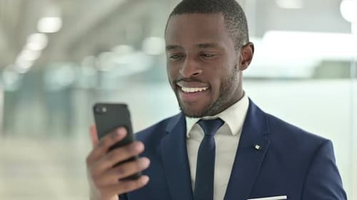 Smiling Man Using Smartphone in Office Setting