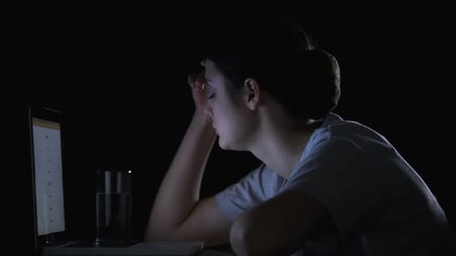 Woman Takes Medication While Working on Laptop at Night