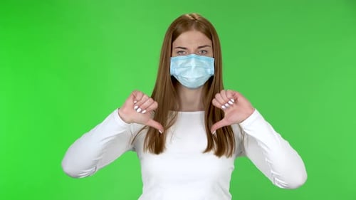 Masked Woman Gives Two Thumbs Down on Green Screen