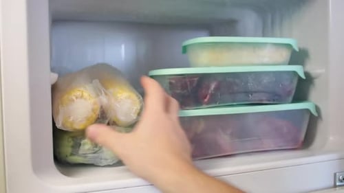 Hand Reaching into Freezer for Frozen Corn
