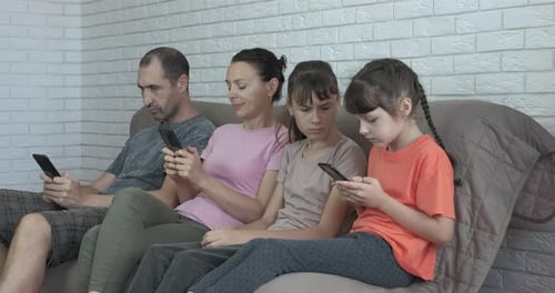 Family Using Cell Phones Together on Sofa