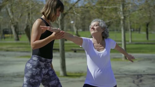 Cheerful Senior Woman and Young Woman Practicing Yoga in Park