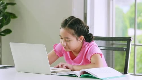 Focused Girl Uses Laptop for Home Schooling