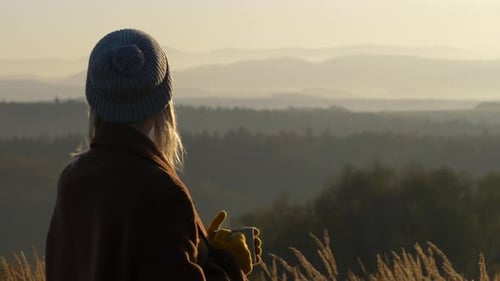 Woman enjoying morning mountain view with coffee