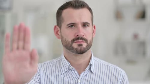 Portrait d'un jeune homme sérieux montrant le panneau d'arrêt avec la main