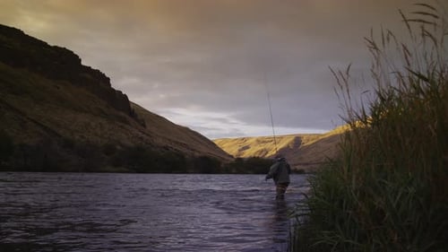 Man fly fishing in beautiful river at sunrise