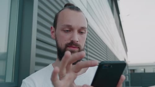 Man With Beard Using Smartphone in Urban Setting