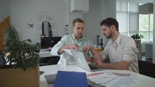 Men Discussing Charts and Graphs in Office
