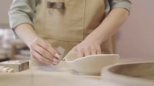 Artisan Smoothing and Brushing Ceramic Bowl in Studio
