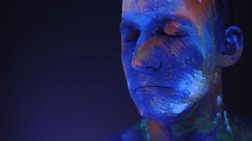 Closeup of a Man's Face in Bright Multicolored Ultraviolet Patterns in the Dark