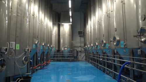 Schwenkaufnahme von Reihen großer Stahltanks mit Bier in einer industriellen Brauereianlage