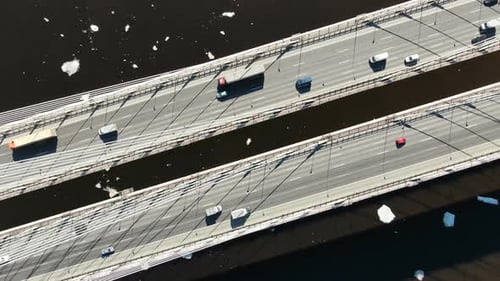 Aerial View of Trucks and Cars Driving on a Cable-stayed Bridge Over the River
