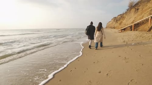 Happy Couple Walking on the Wild Beach on Cloudy Sunrise or Sunset