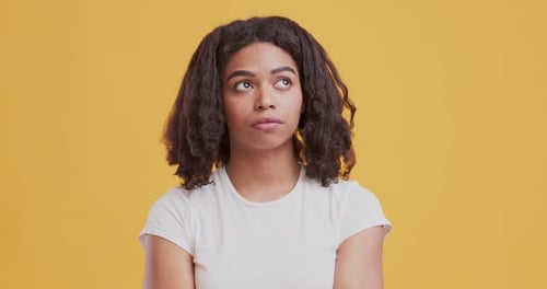 Black Doubtful Girl Thinking Over Orange Studio Background