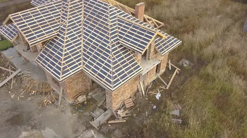 Aerial view of a house under construction works. Unfinished brick building with wooden frame
