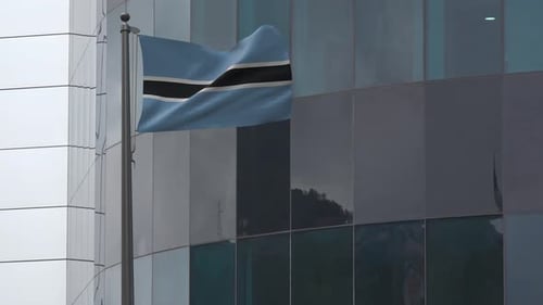Botswana Flag Waving on Pole Against Modern Building