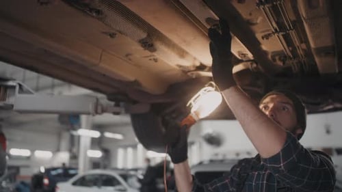 Mechanic Working Underneath Car with Light