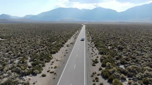Aerial View of Travel Car Driving on Asphalt Road in the Middle of Dusty Dry Desert Land