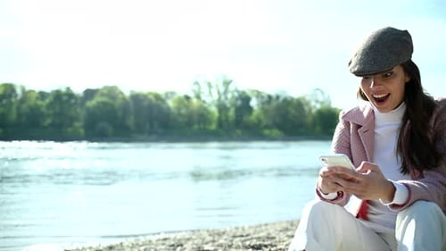 Woman Celebrates Good News on Smartphone at Beach