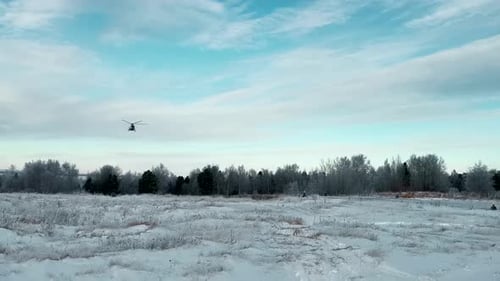 Aterragem de helicóptero em um campo nevado com a floresta e céu nublado no fundo