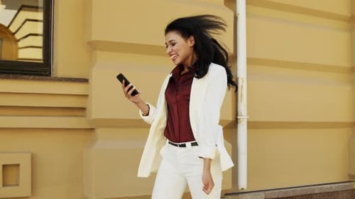 Empresaria ganadora recibe un buen mensaje en un teléfono inteligente sobre un fondo urbano