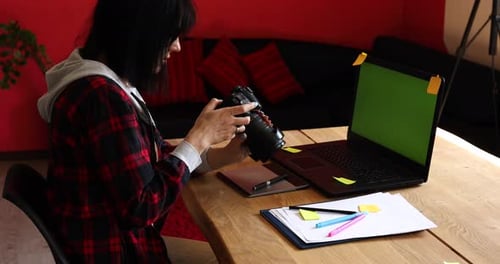 Femme photographe travaillant dans un bureau créatif tenant un appareil photo au bureau et retouche photo