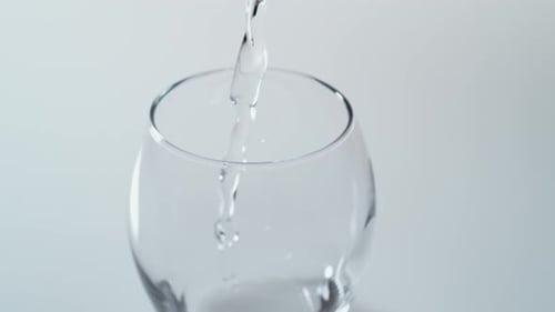 Camera follows pouring water into glass. Slow Motion.