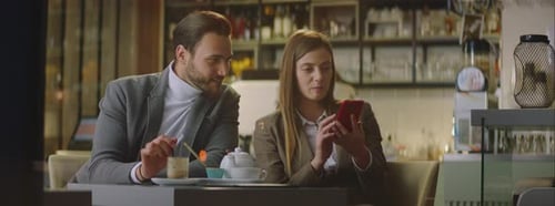 Young Adults at Cafe Table Look at Phone Screen