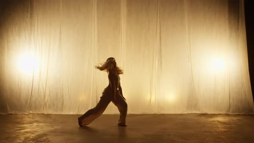 Silhouette of a Professional Dancer Performing in Studio in Soft Warm Lighting