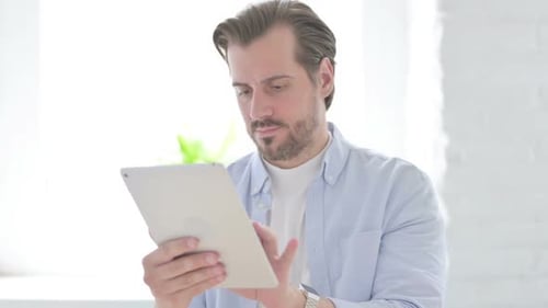 Young Man Browsing Internet on Tablet
