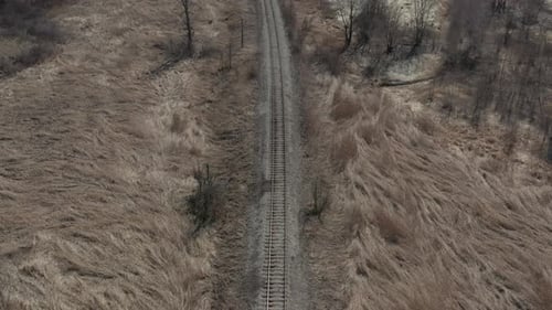 Eisenbahnlinie im Feld mit trockenen Pflanzen 4K-Luftbild