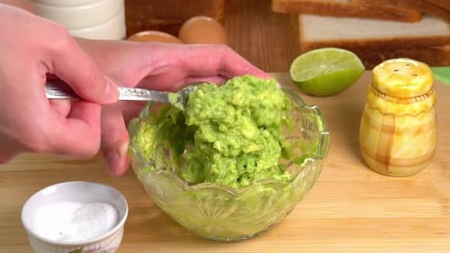 Hands Mashing Avocado with Fork to Make Dip