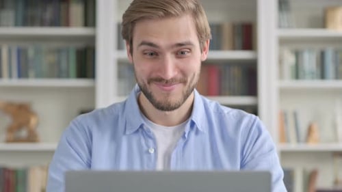 Excited Man Celebrating Success on Laptop Indoors
