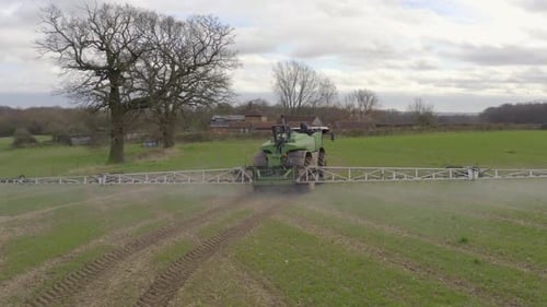 Tractor Sprays Fertilizer in Rural Farm Field