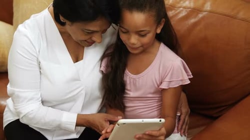 Woman and Child Using Tablet Together on Couch