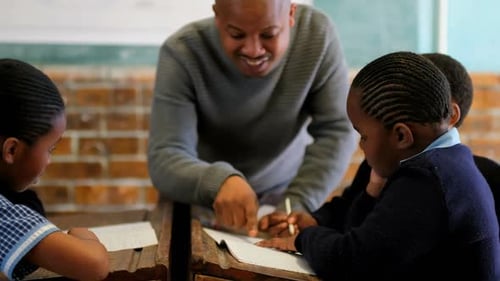 Teacher Helping Students Write in Classroom