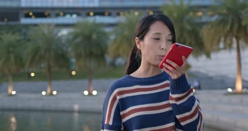 Woman use of voice message on mobile phone in city at night