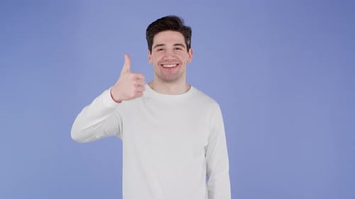Joven apuesto muestra el pulgar hacia arriba como un gesto