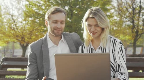 Two Business Colleagues Using Laptop at the Park Together